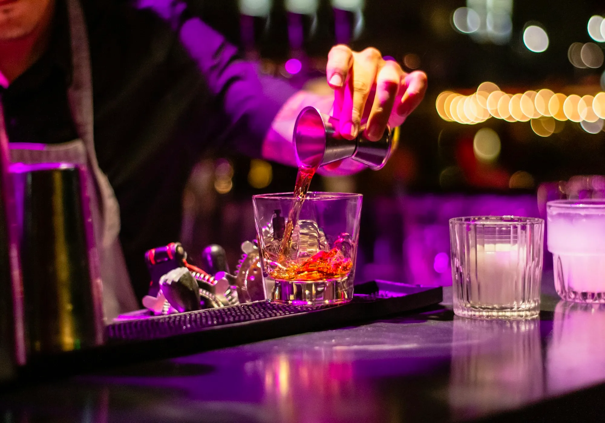 Un barman sert un cocktail sous une lumière violette